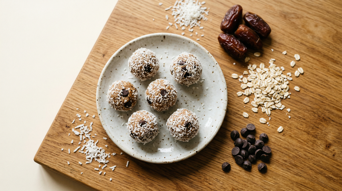 Coconut-rolled ginger energy balls on a speckled plate with dates, oats and chocolate chips