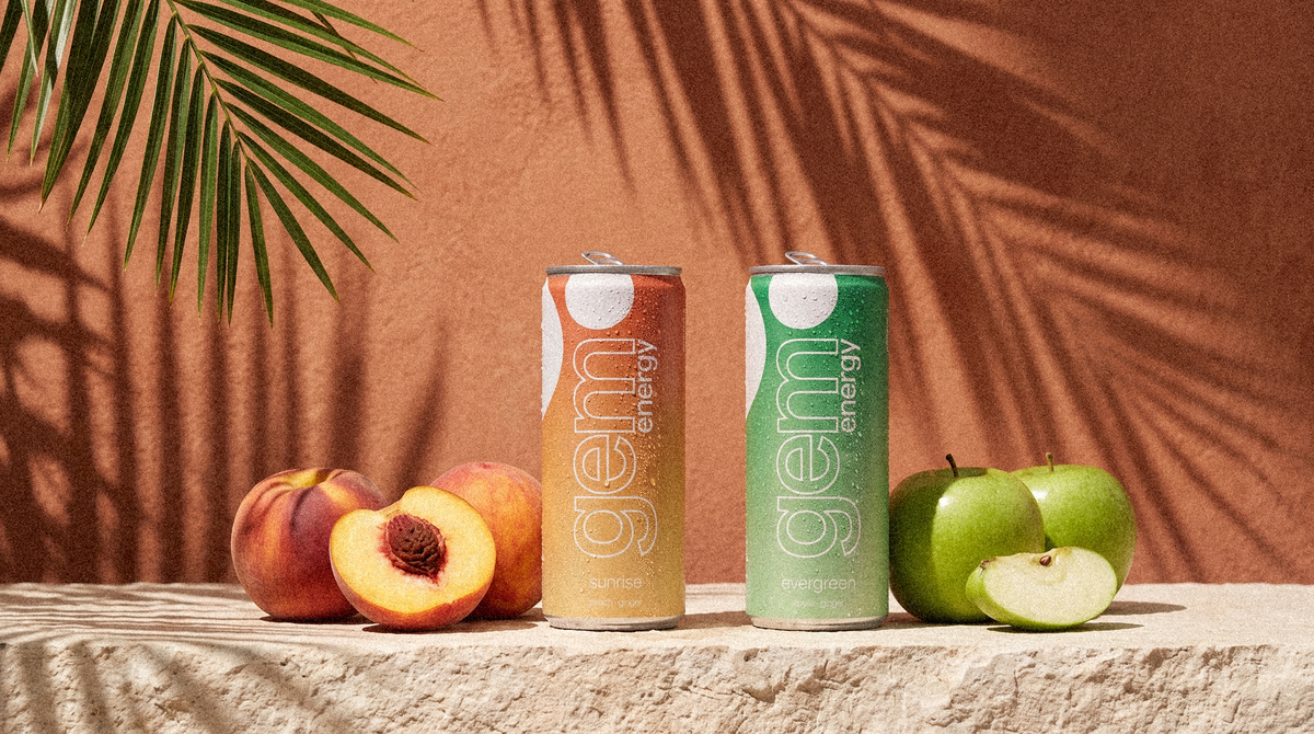 Gem Energy Sunrise and Evergreen cans on a sunlit stone ledge with peaches and green apples