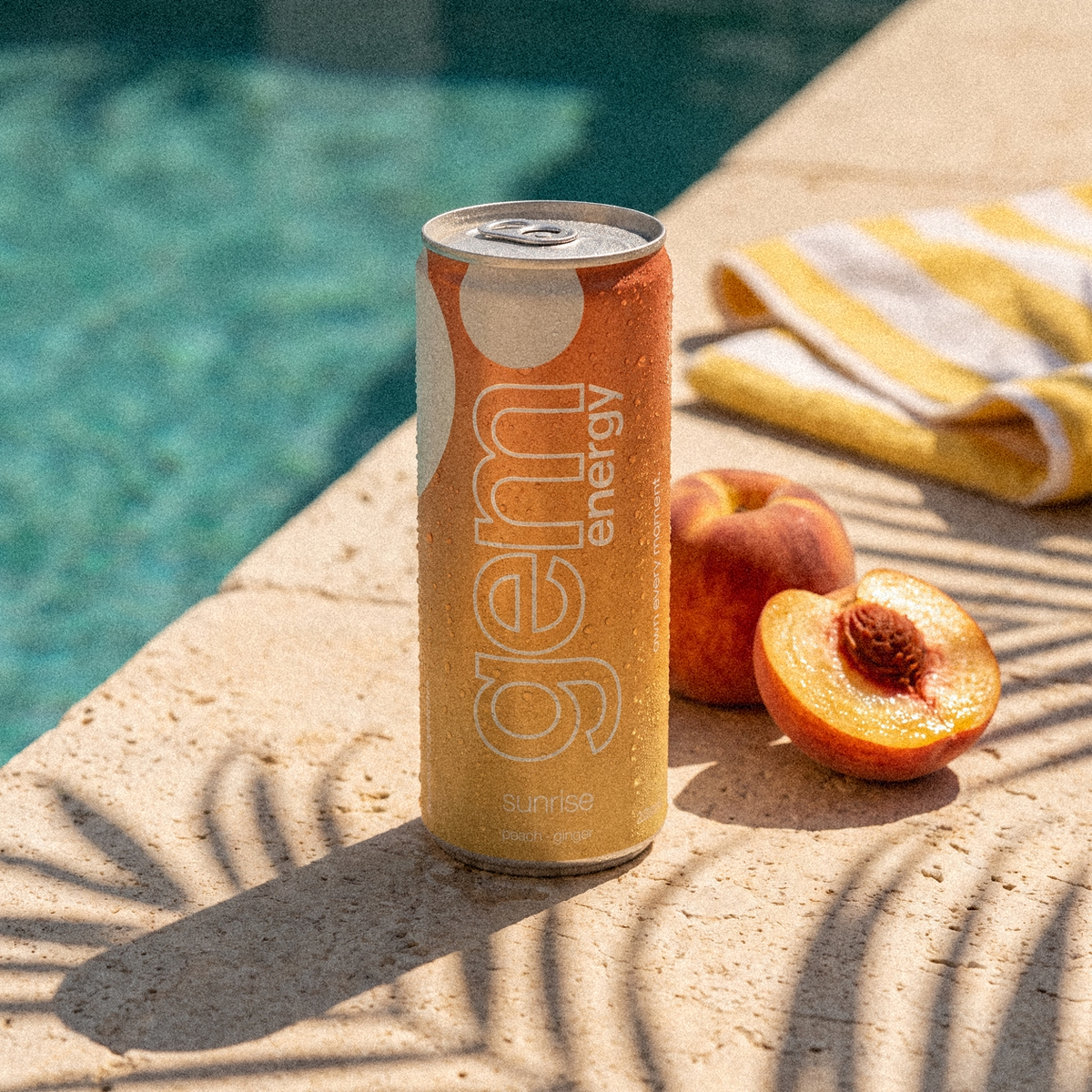 Gem Energy Sunrise can on a sunny pool edge with peaches and a striped towel
