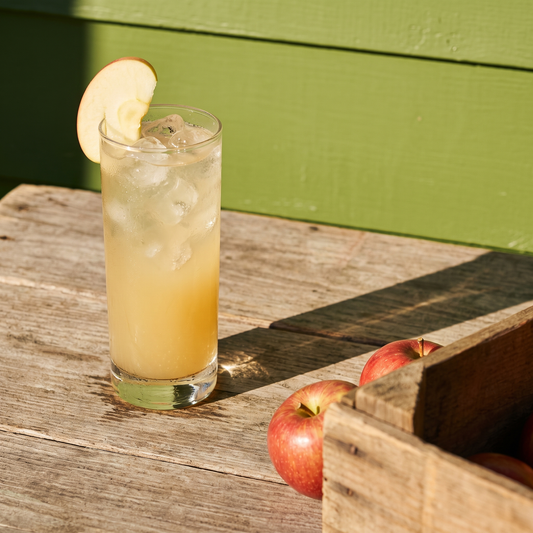 Gem Juice Apple ginger drink served over ice with a fresh apple slice on a wooden crate table